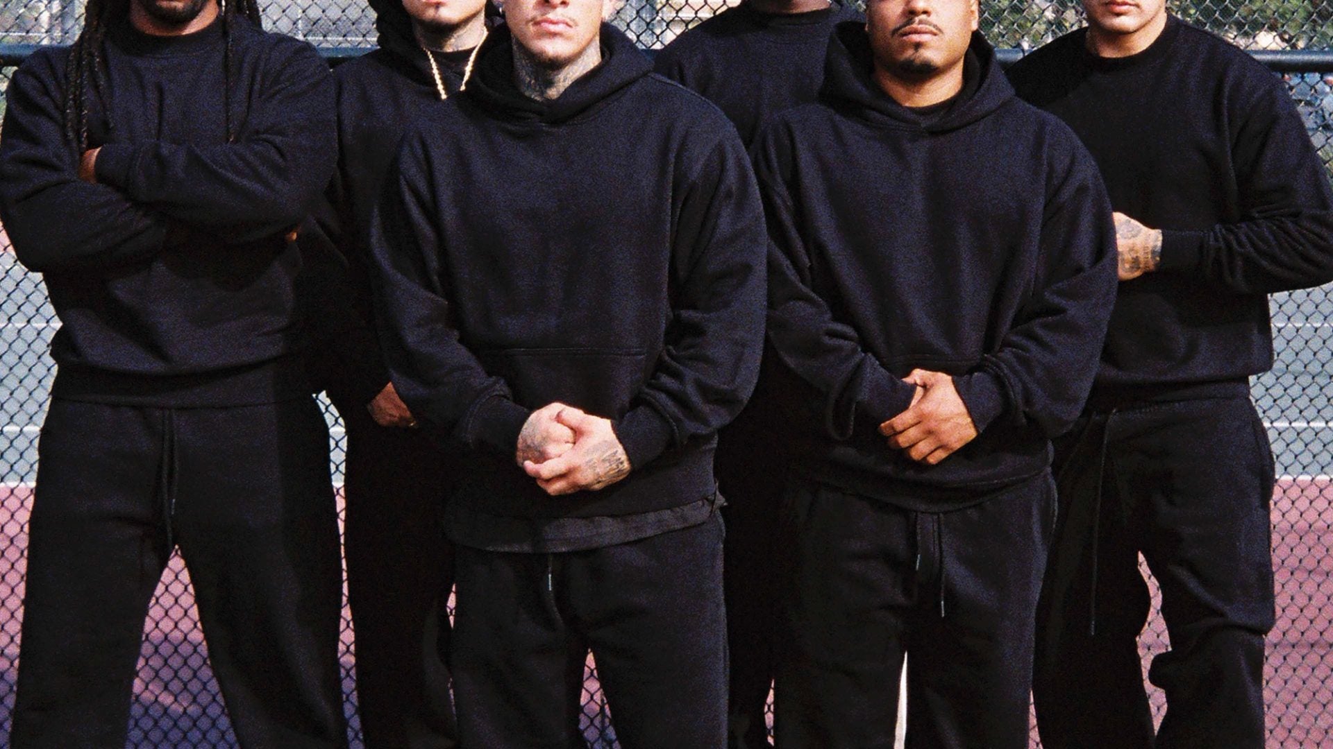 Group wearing matching black hoodies and sweatpants at a basketball court